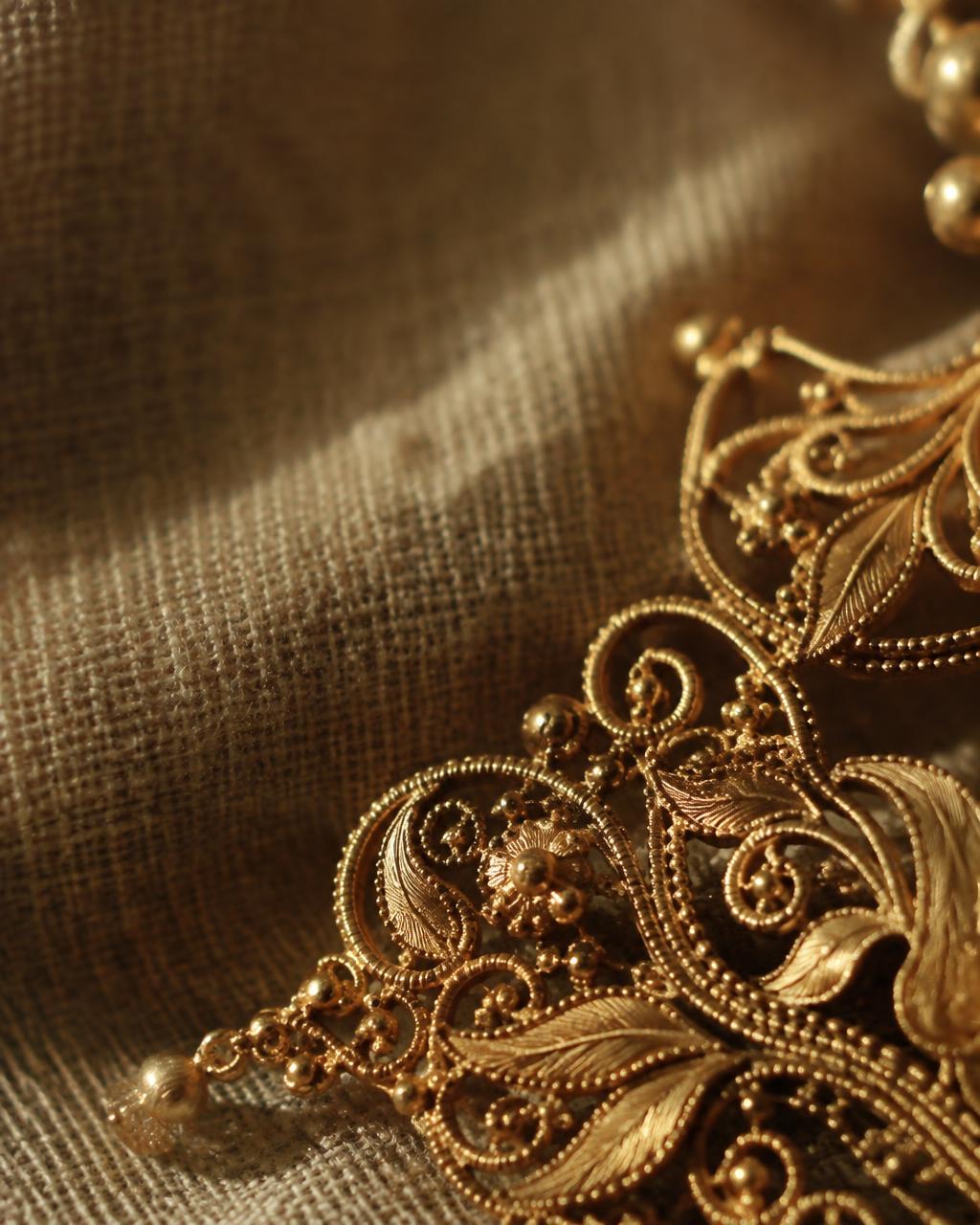 Close detail of gold filigree resting on linen